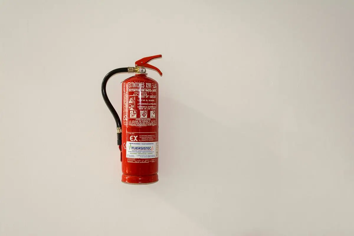 A clearly visible red fire extinguisher installed on a light wall