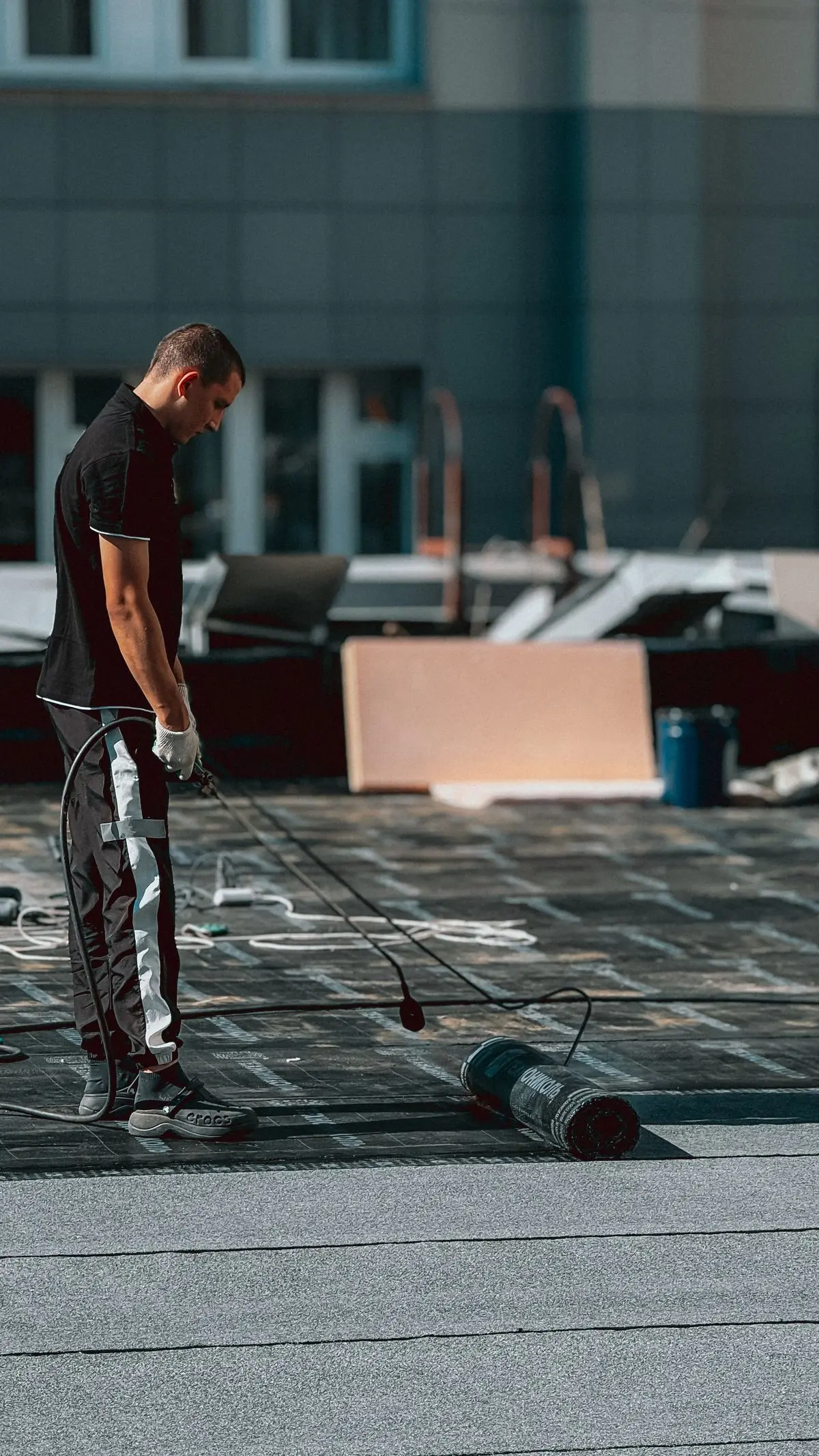 A worker installing waterproofing across a rooftop