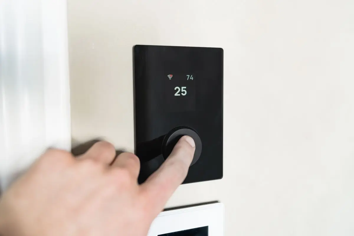 A hand operating a wall-mounted smart heating controller